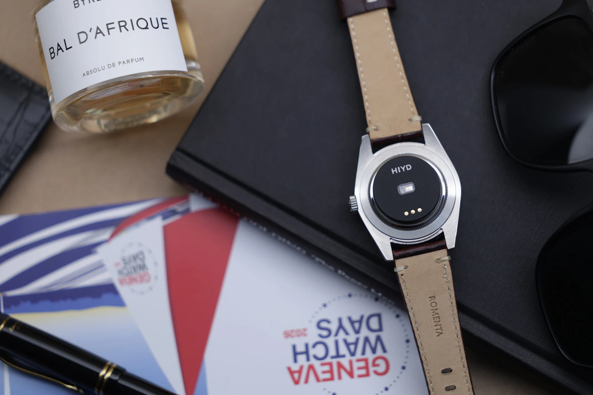 HIYD sensor fitted to the case-back of a steel watch on a leather strap, Geneva Watch Days flatlay