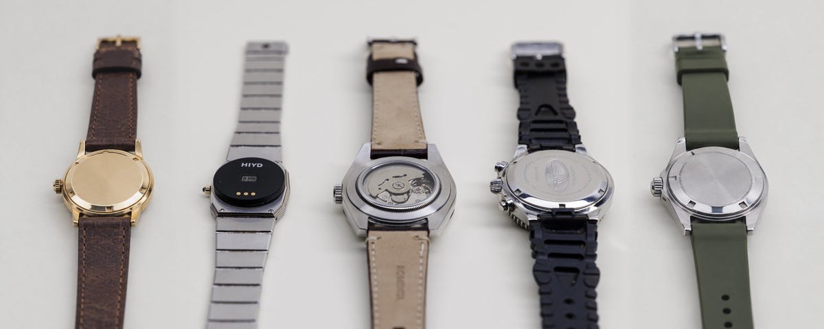 Five watches turned over in a row, one with the HIYD sensor fitted to its caseback
