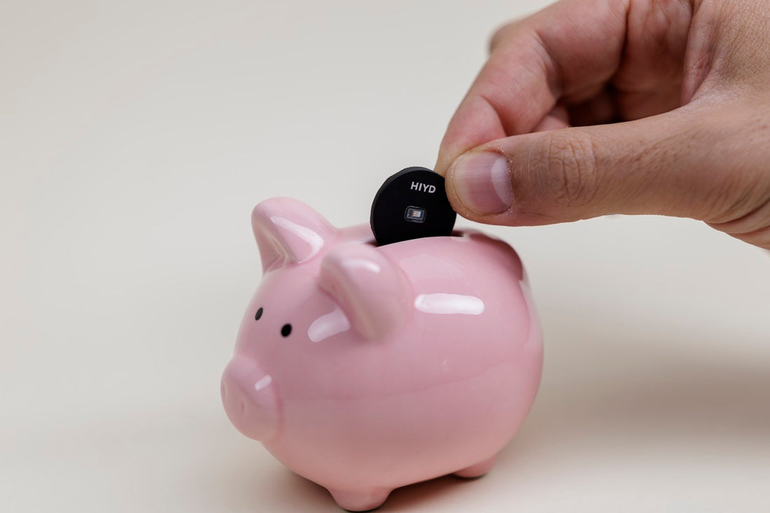 A hand dropping the HIYD sensor into a pink piggy bank