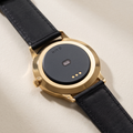 The Hiyd tracker seated on the caseback of a slim gold dress watch